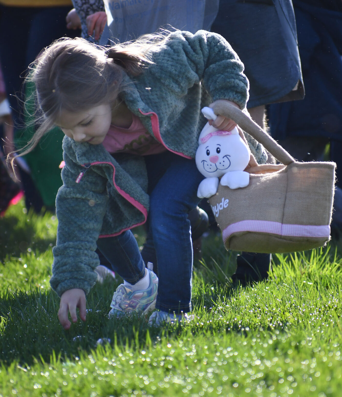 A little girl scoops up an Easter egg